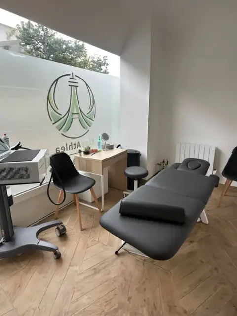 Salle de soin avec table de kinésithérapie et logo KineAthlea au mur